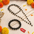 Black beaded necklace and bracelet with a free tag on a textured surface with decorative flowers.