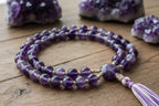 please give me good image of mala that is of 108 +1 bead of amathyst crystal mala should look real aslo make background mala on wood and cluster of amathyst in back 